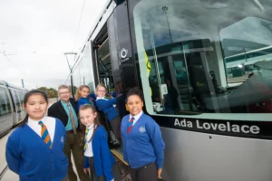 A group of school children standing next to the Ada Lovelace tram. 